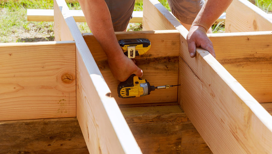 Full length of carpenter drilling wood at construction