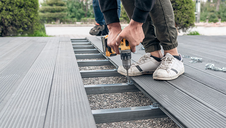 Man assembling composite deck using cordless screwdriver